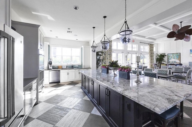 kitchen featuring stainless steel appliances, a spacious island, pendant lighting, white cabinets, and sink