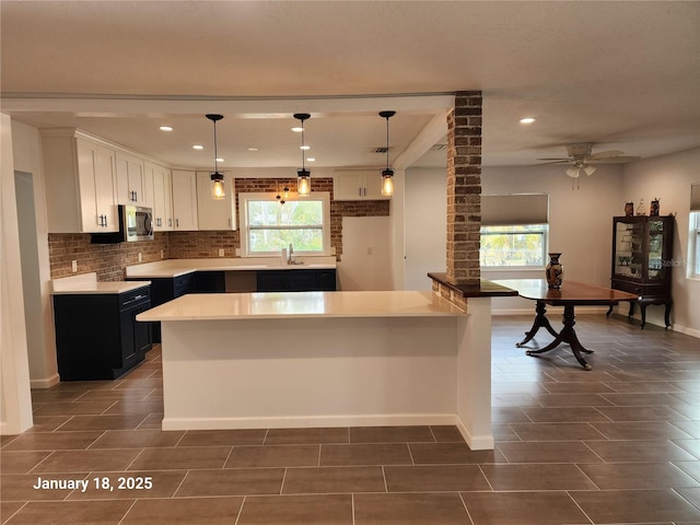 kitchen with ceiling fan, tasteful backsplash, decorative light fixtures, white cabinets, and sink