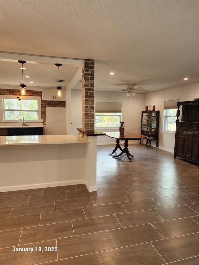 kitchen with decorative light fixtures, ceiling fan, kitchen peninsula, sink, and a textured ceiling