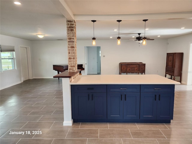 kitchen featuring ceiling fan, blue cabinetry, pendant lighting, and ornate columns