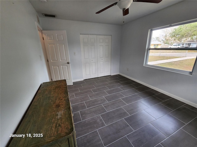 unfurnished bedroom with ceiling fan and a closet