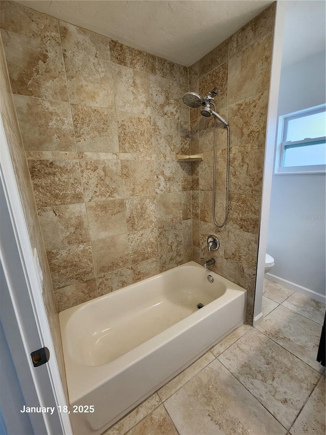 bathroom with toilet and tiled shower / bath