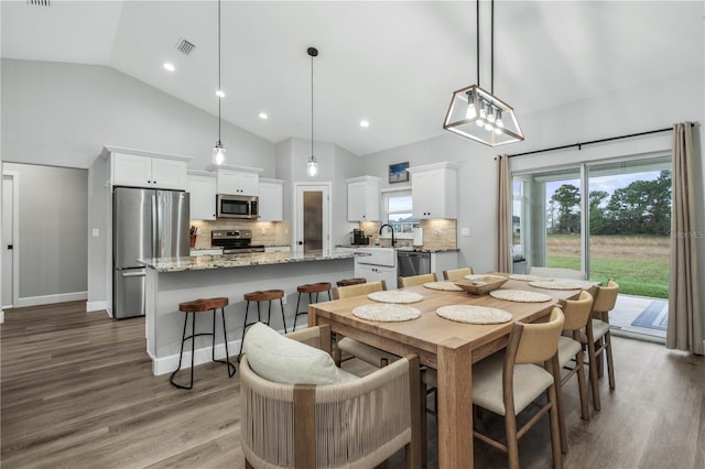 dining room featuring high vaulted ceiling, sink, and hardwood / wood-style flooring