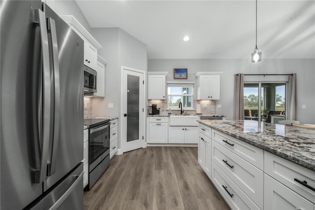 kitchen with pendant lighting, decorative backsplash, sink, white cabinetry, and appliances with stainless steel finishes