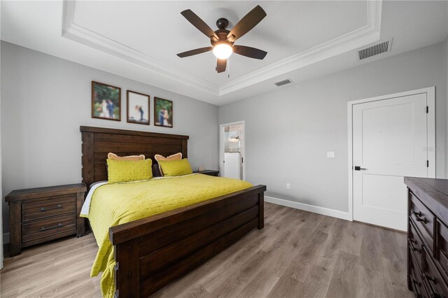 bedroom featuring ceiling fan, a tray ceiling, and light hardwood / wood-style floors