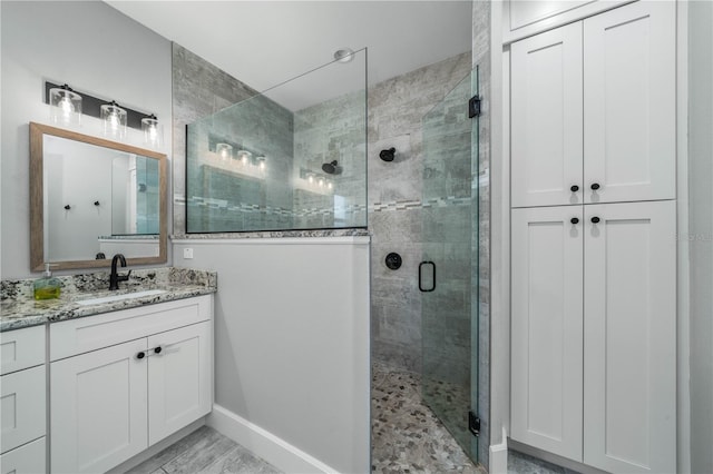 bathroom featuring a shower with shower door and vanity