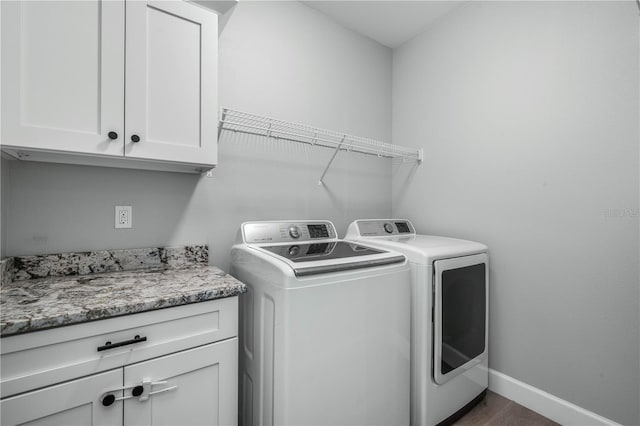 laundry room featuring cabinets, dark hardwood / wood-style floors, and washing machine and clothes dryer