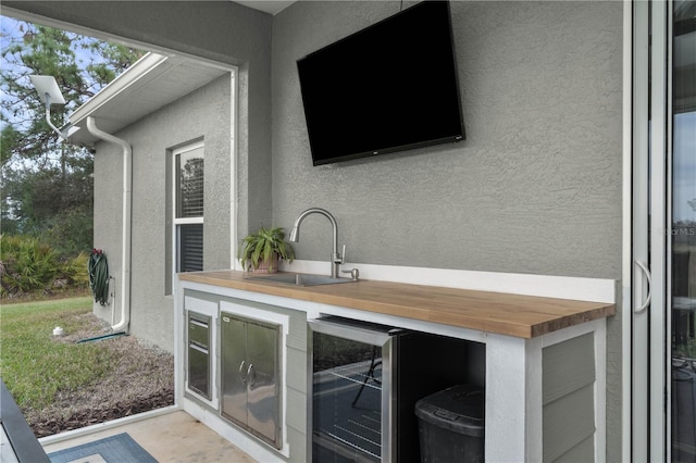 exterior space with wine cooler, wooden counters, and sink