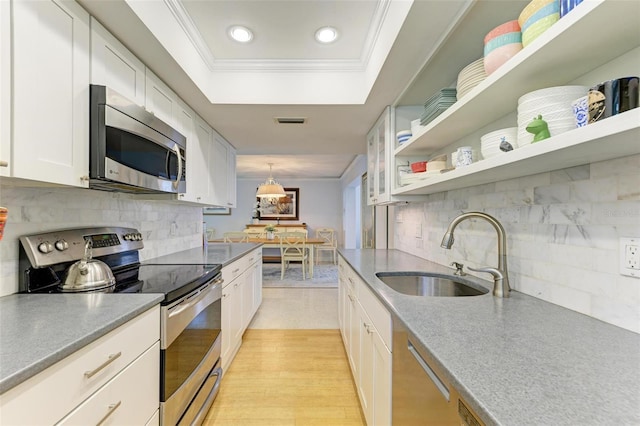 kitchen featuring white cabinetry, stainless steel appliances, decorative backsplash, sink, and hanging light fixtures