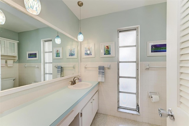 bathroom featuring vanity, toilet, and tile walls