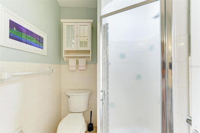 bathroom featuring a shower with door, toilet, and tile walls