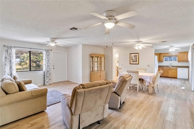 living room with a textured ceiling, light hardwood / wood-style floors, and sink