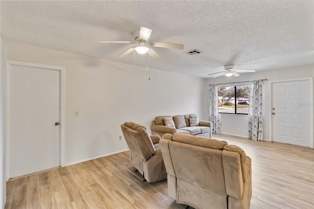 living room with a textured ceiling, ceiling fan, and light hardwood / wood-style flooring