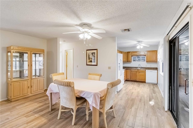 dining room with light wood-type flooring, ceiling fan, a textured ceiling, and sink