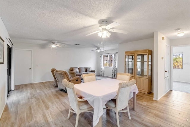 dining area with a textured ceiling, light wood-type flooring, and a healthy amount of sunlight