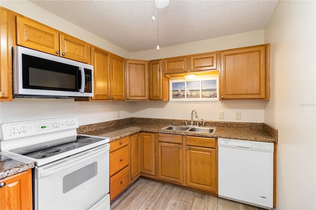 kitchen with a textured ceiling, sink, light hardwood / wood-style flooring, and white appliances