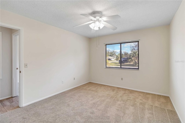 spare room featuring light carpet, ceiling fan, and a textured ceiling