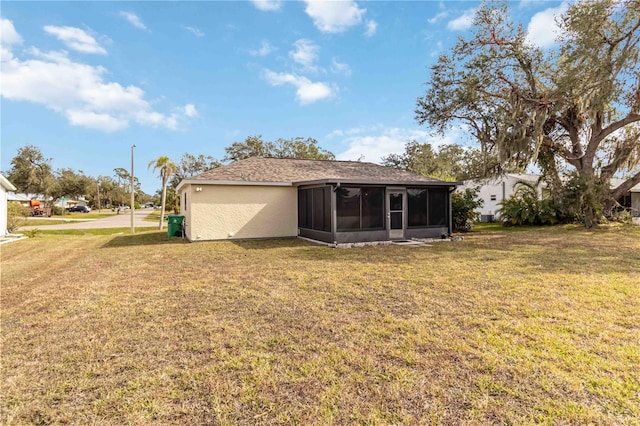 rear view of property featuring a yard and a sunroom