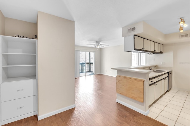 kitchen with white cabinetry, sink, light wood-type flooring, ceiling fan, and stainless steel dishwasher