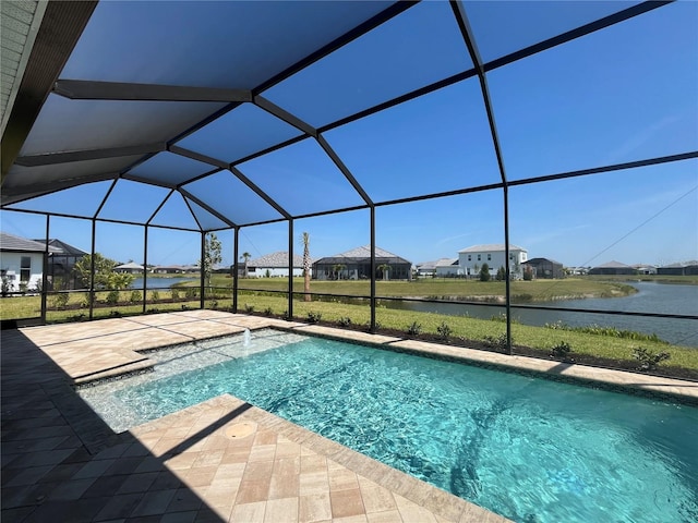 view of pool with a patio area, glass enclosure, and a water view