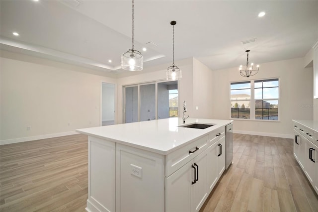 kitchen with stainless steel dishwasher, a sink, baseboards, visible vents, and light wood-style floors
