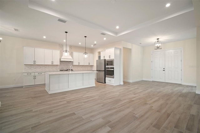 kitchen with open floor plan, decorative backsplash, white cabinetry, and appliances with stainless steel finishes
