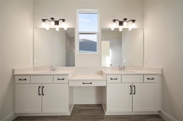 full bath with two vanities, baseboards, a sink, and a walk in shower