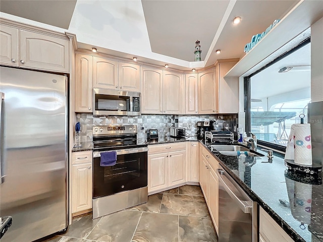 kitchen with decorative backsplash, sink, stainless steel appliances, and dark stone counters