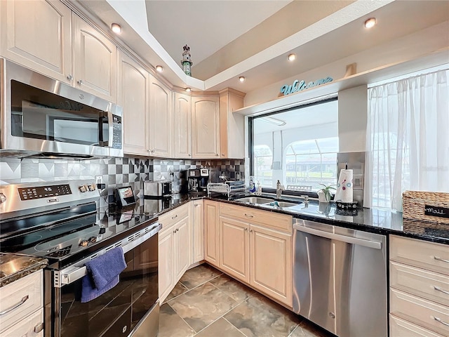 kitchen featuring sink, backsplash, stainless steel appliances, and dark stone countertops