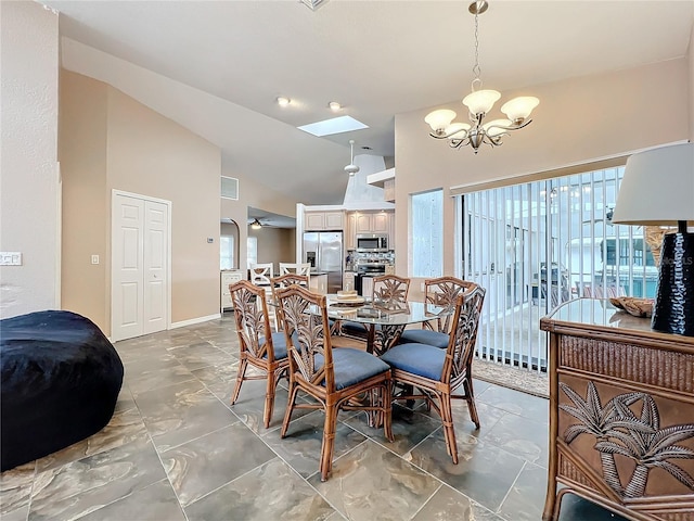 dining room featuring lofted ceiling with skylight and ceiling fan with notable chandelier