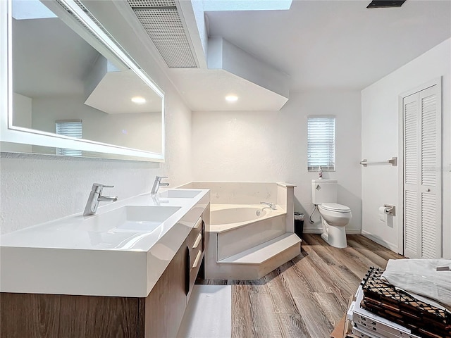 bathroom with toilet, vanity, a bath, and hardwood / wood-style floors