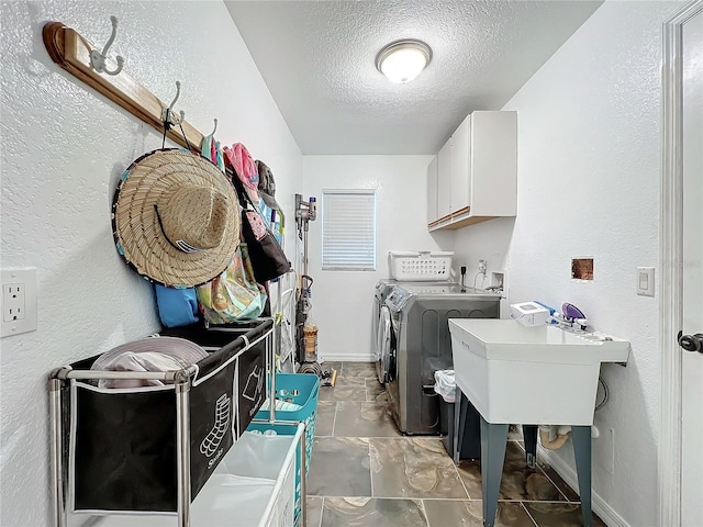 clothes washing area featuring cabinets, a textured ceiling, sink, and independent washer and dryer