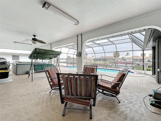 view of patio / terrace featuring glass enclosure, a pool with hot tub, and ceiling fan