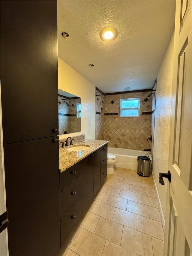 full bathroom featuring a textured ceiling, tiled shower / bath, tile patterned floors, vanity, and toilet