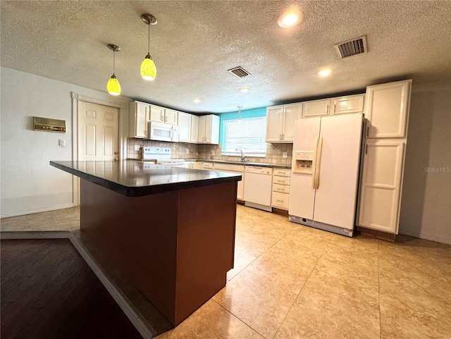 kitchen featuring white appliances, white cabinetry, hanging light fixtures, sink, and backsplash