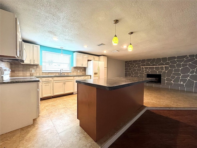 kitchen with pendant lighting, white fridge with ice dispenser, white cabinetry, decorative backsplash, and kitchen peninsula