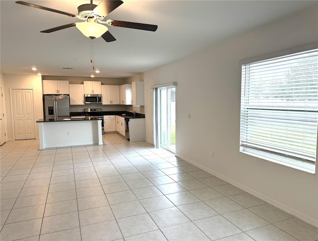 kitchen featuring appliances with stainless steel finishes, white cabinetry, sink, ceiling fan, and light tile patterned floors