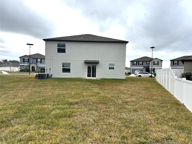 rear view of property featuring cooling unit and a lawn