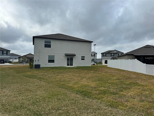 back of property with central AC unit and a yard