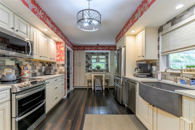 kitchen with stainless steel appliances, sink, backsplash, hanging light fixtures, and dark hardwood / wood-style floors