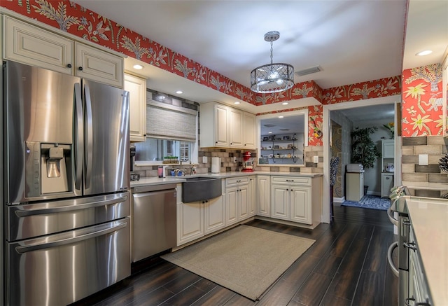 kitchen with dark wood-type flooring, hanging light fixtures, stainless steel appliances, and an inviting chandelier