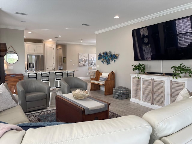 living room with light wood-type flooring, sink, and ornamental molding