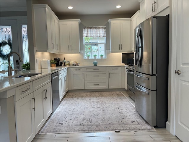 kitchen with appliances with stainless steel finishes, backsplash, white cabinets, and sink