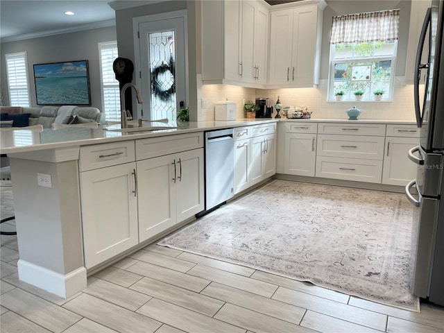 kitchen featuring white cabinets, stainless steel appliances, sink, kitchen peninsula, and ornamental molding