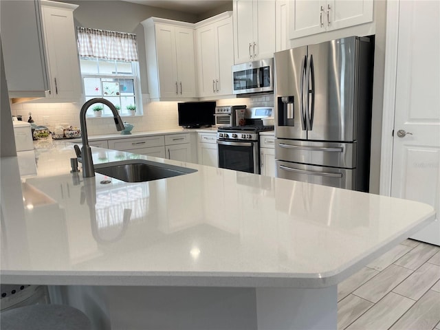 kitchen featuring white cabinetry, stainless steel appliances, tasteful backsplash, sink, and kitchen peninsula