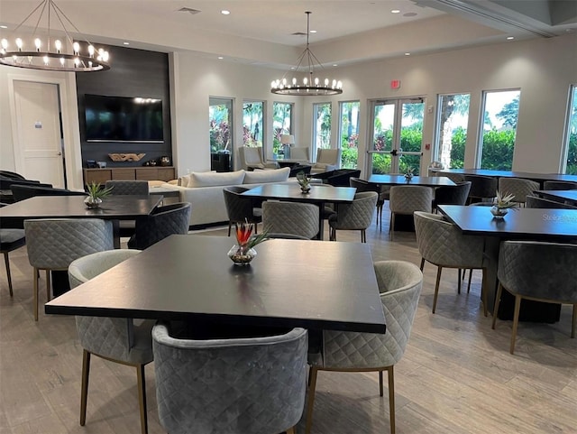 dining space with a chandelier, a raised ceiling, and light hardwood / wood-style flooring