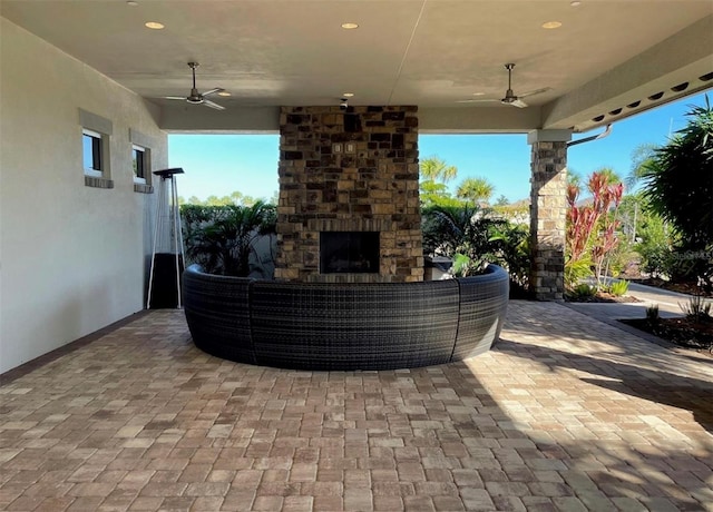 view of patio / terrace featuring ceiling fan and an outdoor living space with a fireplace