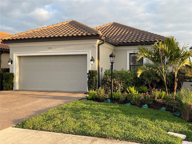 mediterranean / spanish home featuring a garage and a front lawn