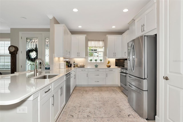 kitchen with appliances with stainless steel finishes, sink, white cabinets, and decorative backsplash