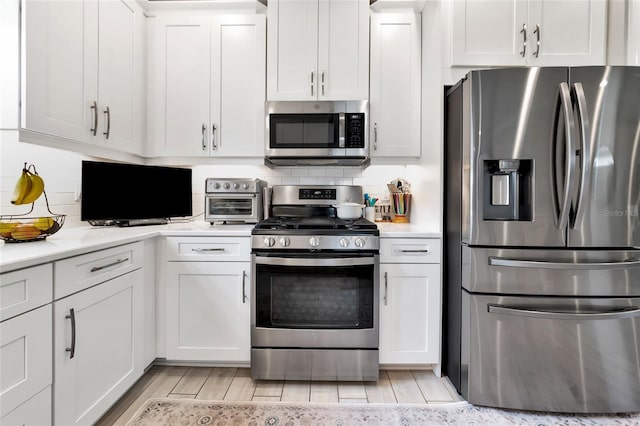 kitchen featuring appliances with stainless steel finishes, decorative backsplash, and white cabinets